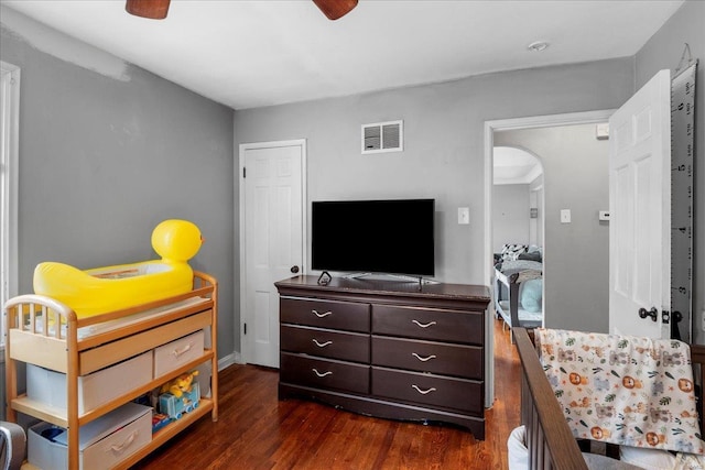 bedroom featuring visible vents, arched walkways, and dark wood finished floors