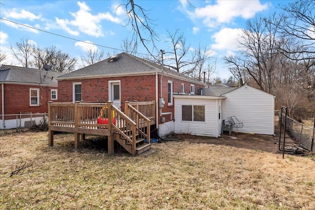 back of property with a shingled roof, a fenced backyard, a deck, a yard, and brick siding