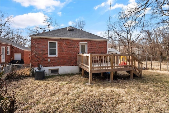 rear view of house featuring brick siding, a shingled roof, central AC unit, fence, and a wooden deck