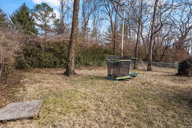 view of yard with a trampoline and fence