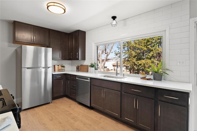 kitchen with a sink, stainless steel appliances, dark brown cabinetry, and light countertops