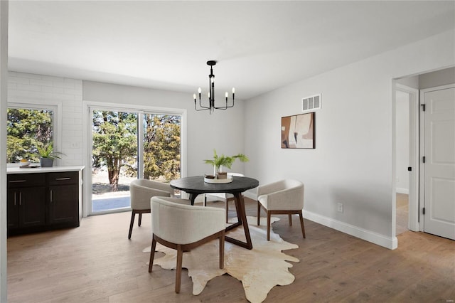 dining space with light wood-type flooring, baseboards, visible vents, and a chandelier