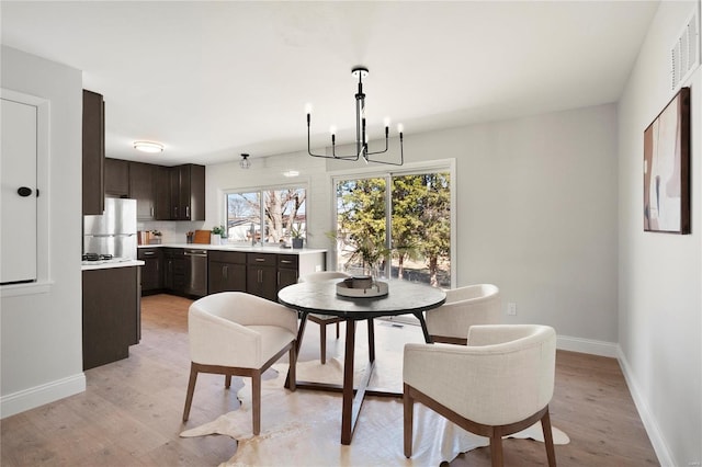 dining area with visible vents, a notable chandelier, baseboards, and light wood-type flooring