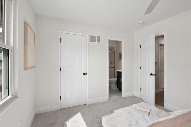 carpeted bedroom featuring visible vents, baseboards, and ensuite bathroom