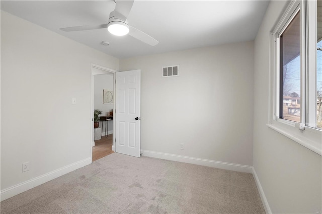 spare room featuring baseboards, visible vents, and light carpet