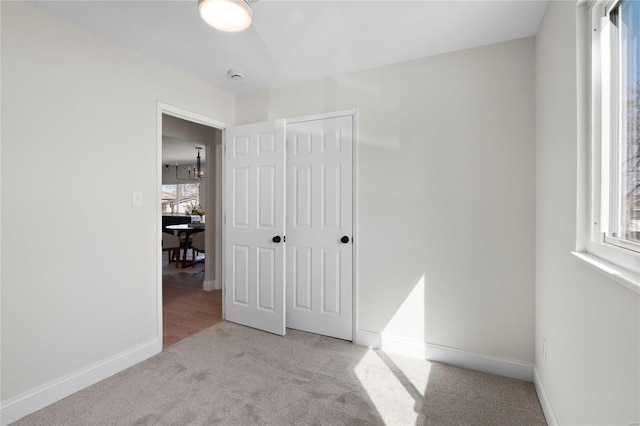 unfurnished bedroom featuring baseboards, multiple windows, and carpet flooring