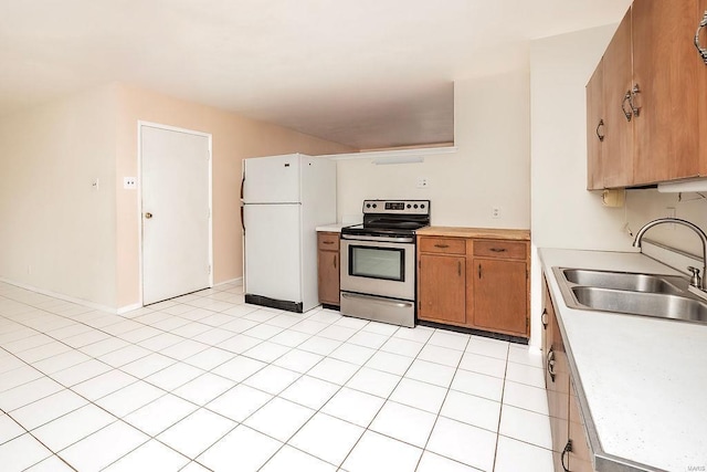 kitchen featuring freestanding refrigerator, light countertops, stainless steel electric range oven, and a sink