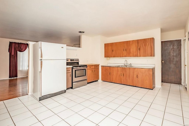 kitchen with light tile patterned flooring, a sink, light countertops, freestanding refrigerator, and stainless steel electric stove