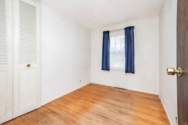 unfurnished bedroom with visible vents, a closet, light wood-style flooring, and baseboards