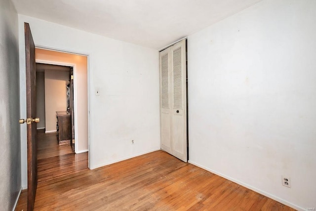 unfurnished bedroom with baseboards, a closet, and light wood-style floors