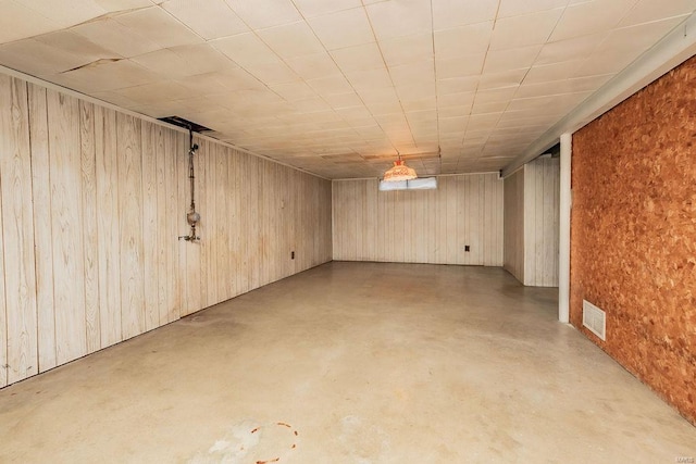 finished basement featuring visible vents and wooden walls