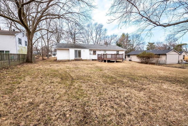 rear view of property with a deck, a lawn, and fence