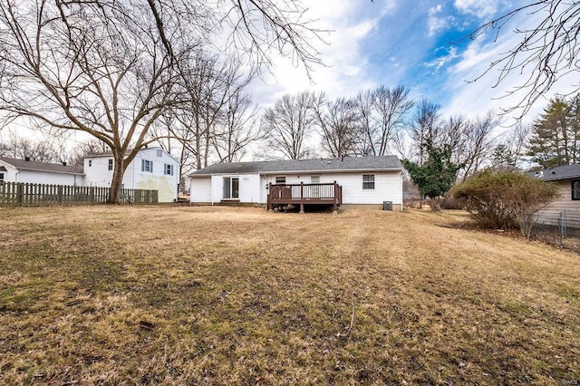 back of house featuring fence, a deck, and a lawn