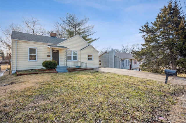 view of front of house with a front lawn, a chimney, and a shingled roof