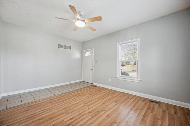 empty room featuring visible vents, ceiling fan, baseboards, and wood finished floors