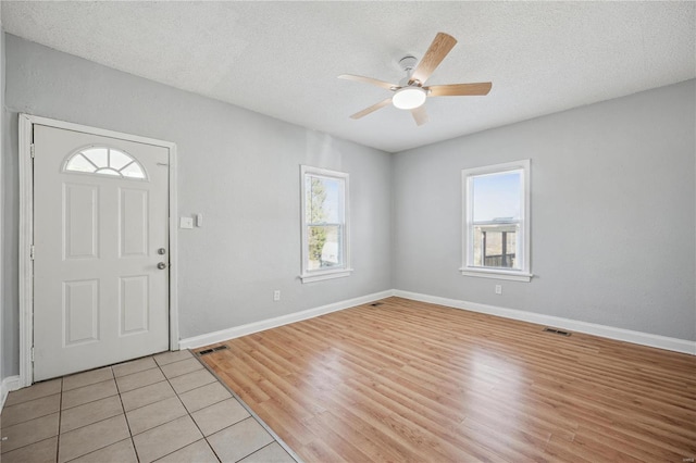 entrance foyer featuring light wood finished floors, plenty of natural light, visible vents, and a textured ceiling