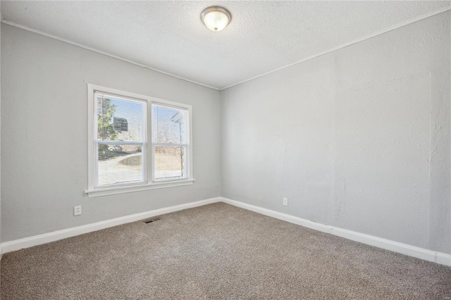 carpeted spare room with baseboards, visible vents, and a textured ceiling