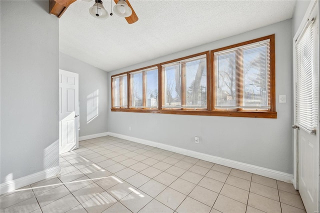 unfurnished room with light tile patterned floors, ceiling fan, a textured ceiling, and baseboards