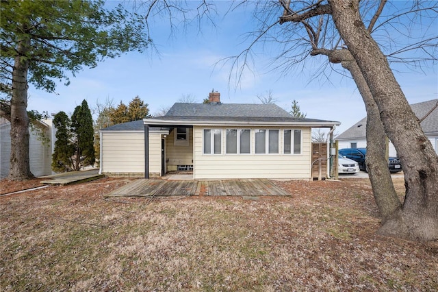 rear view of house featuring roof with shingles and a chimney