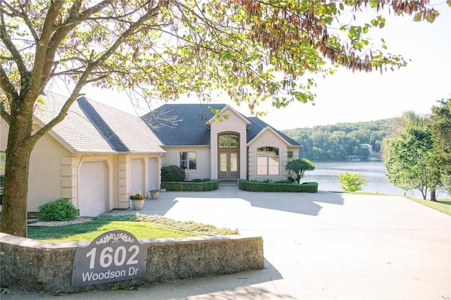 view of front of property with a garage, french doors, a shingled roof, and stucco siding