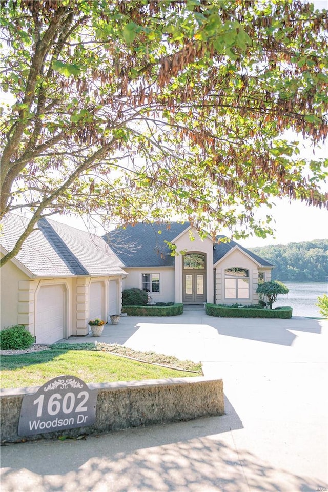 view of front facade with a garage, concrete driveway, and french doors