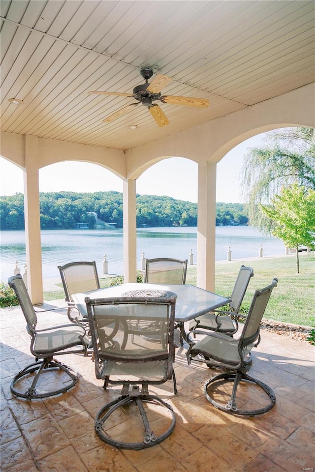 view of patio / terrace featuring outdoor dining area, a water view, and a ceiling fan