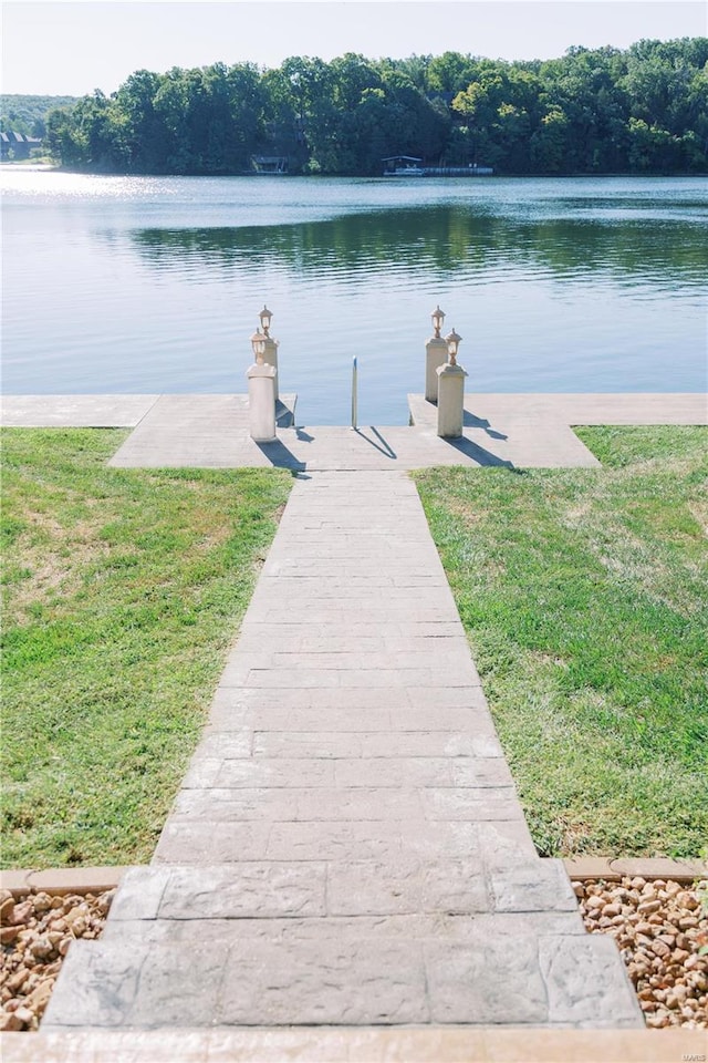 view of dock with a water view and a yard