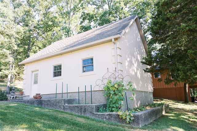 view of side of home featuring a shingled roof, a yard, and stucco siding