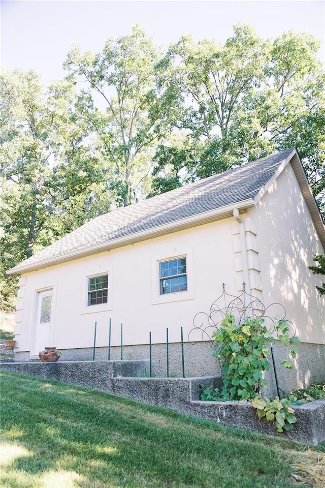 view of property exterior with a yard, roof with shingles, and stucco siding