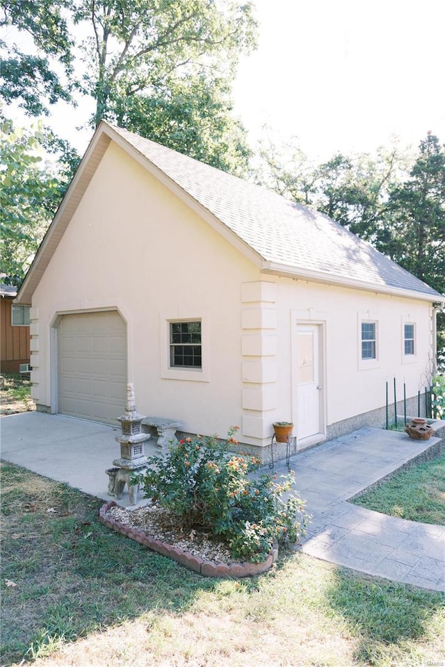 view of side of home featuring a garage, roof with shingles, and stucco siding