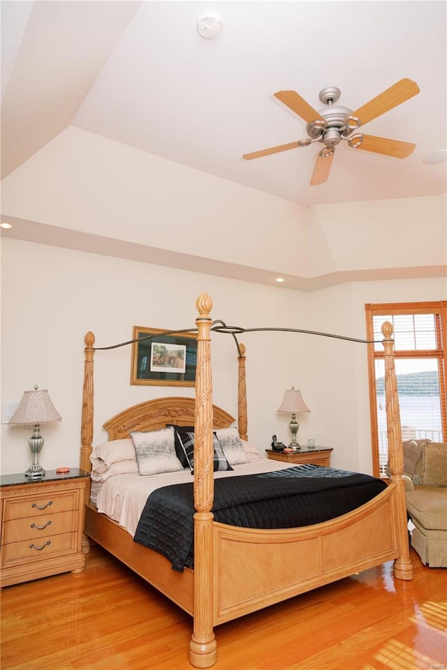 bedroom featuring lofted ceiling, a tray ceiling, light wood finished floors, and ceiling fan