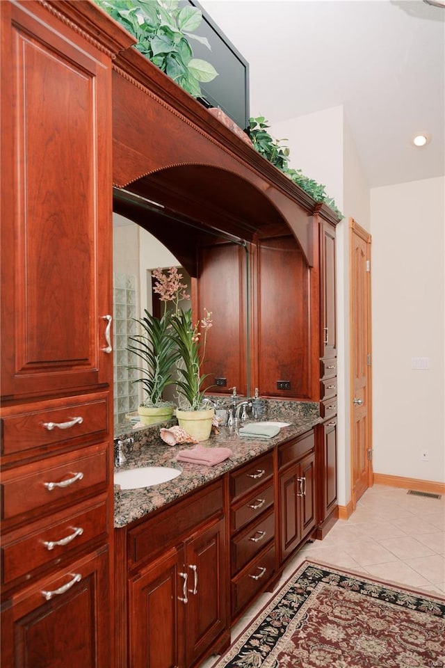 bathroom featuring baseboards, double vanity, a sink, and tile patterned floors