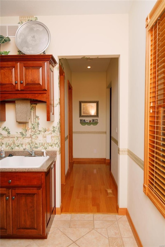 hall with light tile patterned floors, baseboards, and a sink