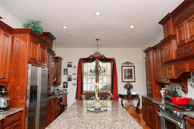 kitchen featuring a chandelier, recessed lighting, stainless steel appliances, light stone countertops, and decorative light fixtures