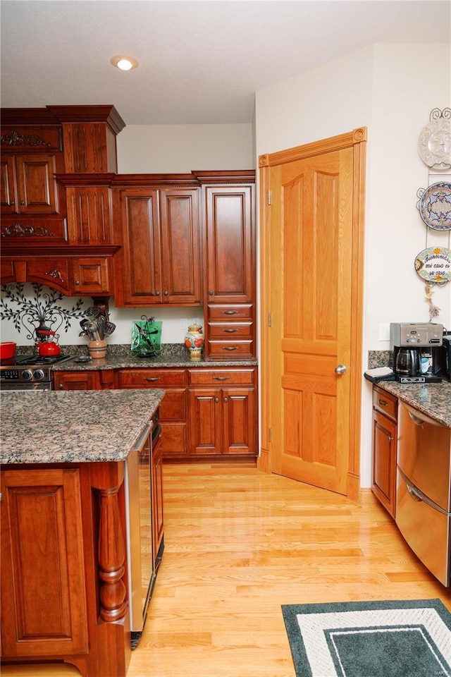 kitchen with light wood-style floors, stainless steel range with gas cooktop, dark stone counters, and recessed lighting