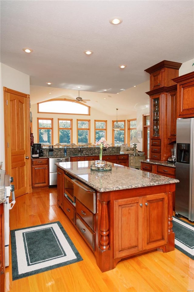 kitchen with stainless steel appliances, light wood-style floors, vaulted ceiling, a center island, and a warming drawer