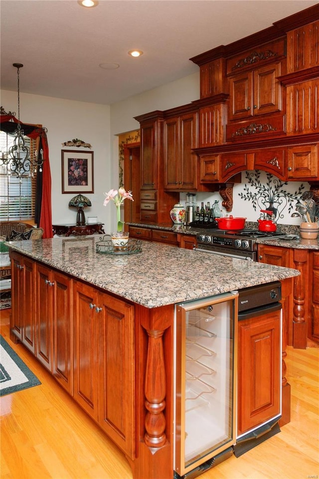 kitchen with stainless steel range with gas cooktop, wine cooler, light wood-style flooring, and a center island