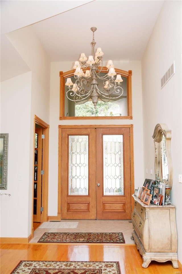 foyer entrance featuring a chandelier, wood finished floors, and visible vents