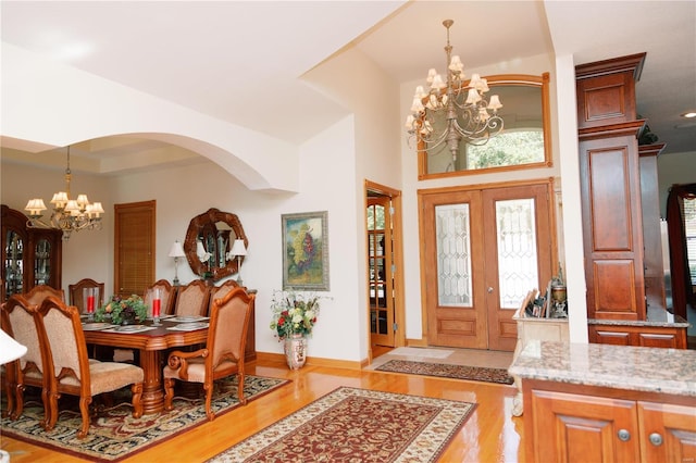 entryway featuring light wood-type flooring, an inviting chandelier, baseboards, and french doors