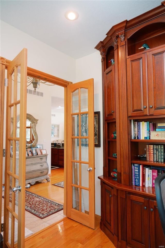 interior space with light wood finished floors, french doors, and visible vents