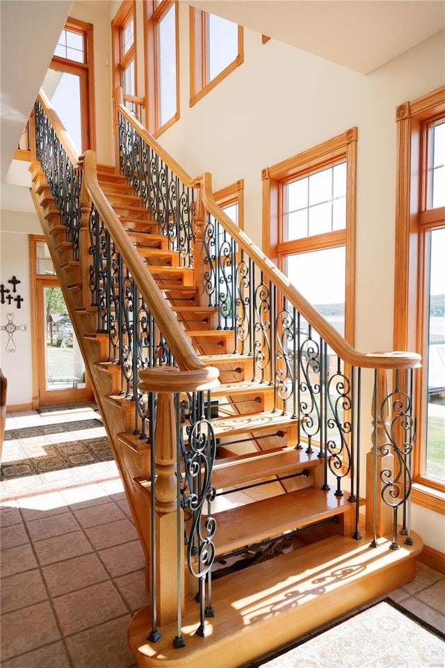 stairway featuring a towering ceiling and baseboards