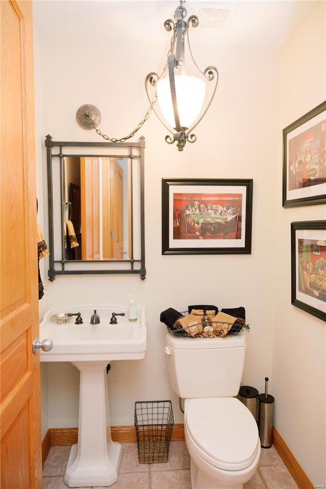 half bath with toilet, baseboards, and tile patterned floors