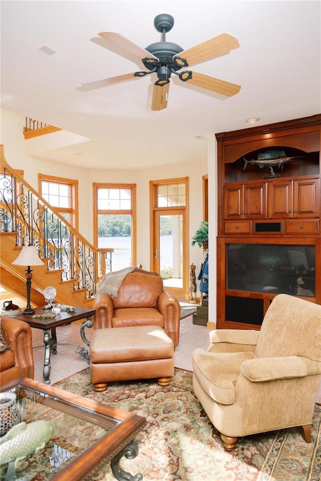 living room with ceiling fan, stairway, and light tile patterned flooring