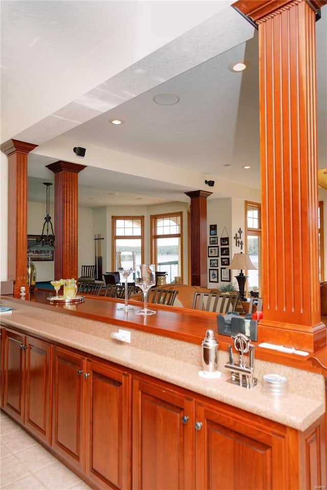 kitchen with ornate columns, recessed lighting, open floor plan, and brown cabinetry