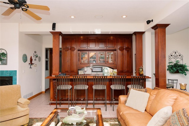 living room with indoor bar, a fireplace, light tile patterned floors, visible vents, and ornate columns