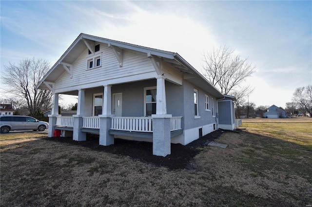 view of side of home featuring a porch and a lawn