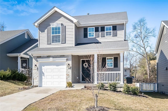 traditional-style house with a porch, a garage, concrete driveway, stone siding, and a front yard