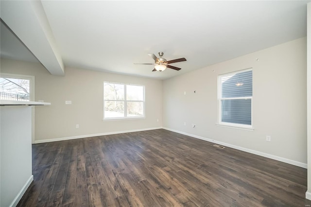 spare room featuring ceiling fan, dark wood-style flooring, visible vents, and baseboards