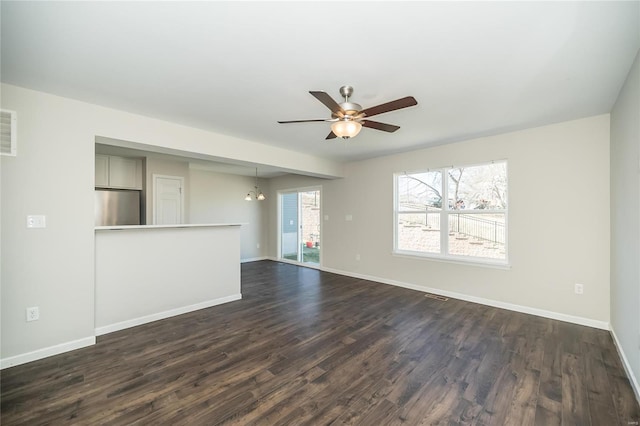 unfurnished living room with dark wood-style floors, baseboards, and ceiling fan with notable chandelier