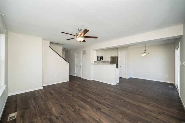 unfurnished living room with dark wood-style floors, visible vents, baseboards, and ceiling fan with notable chandelier